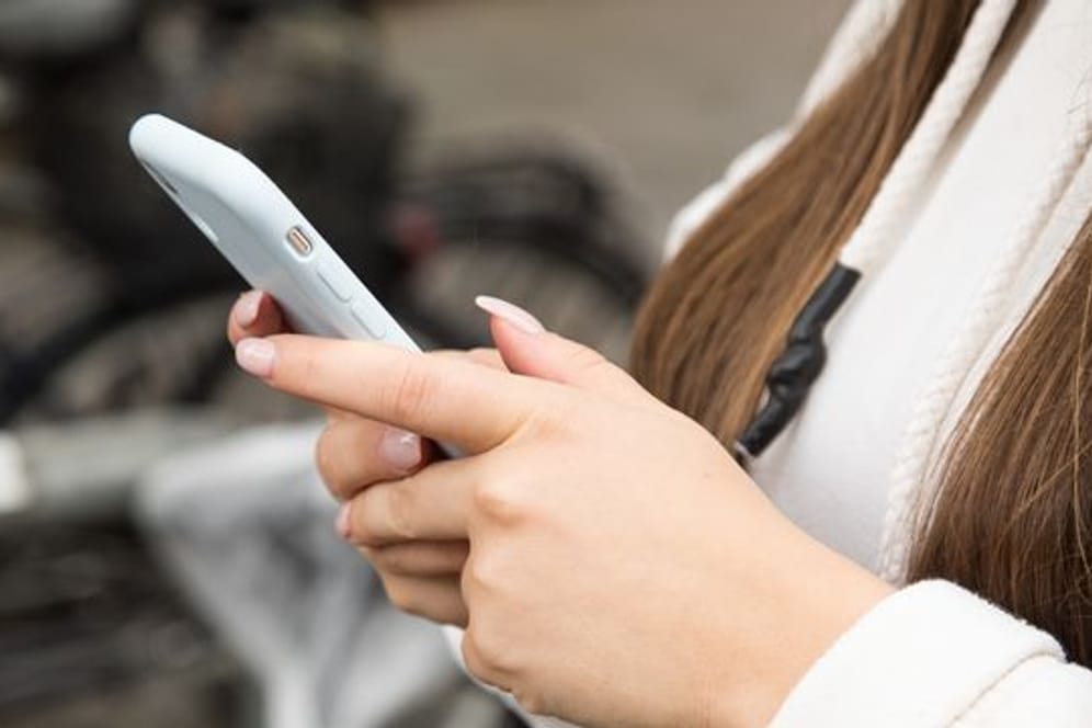 Eine Frau mit Smartphone: Die Berliner Polizei warnt vor einer gefährlichen SMS.