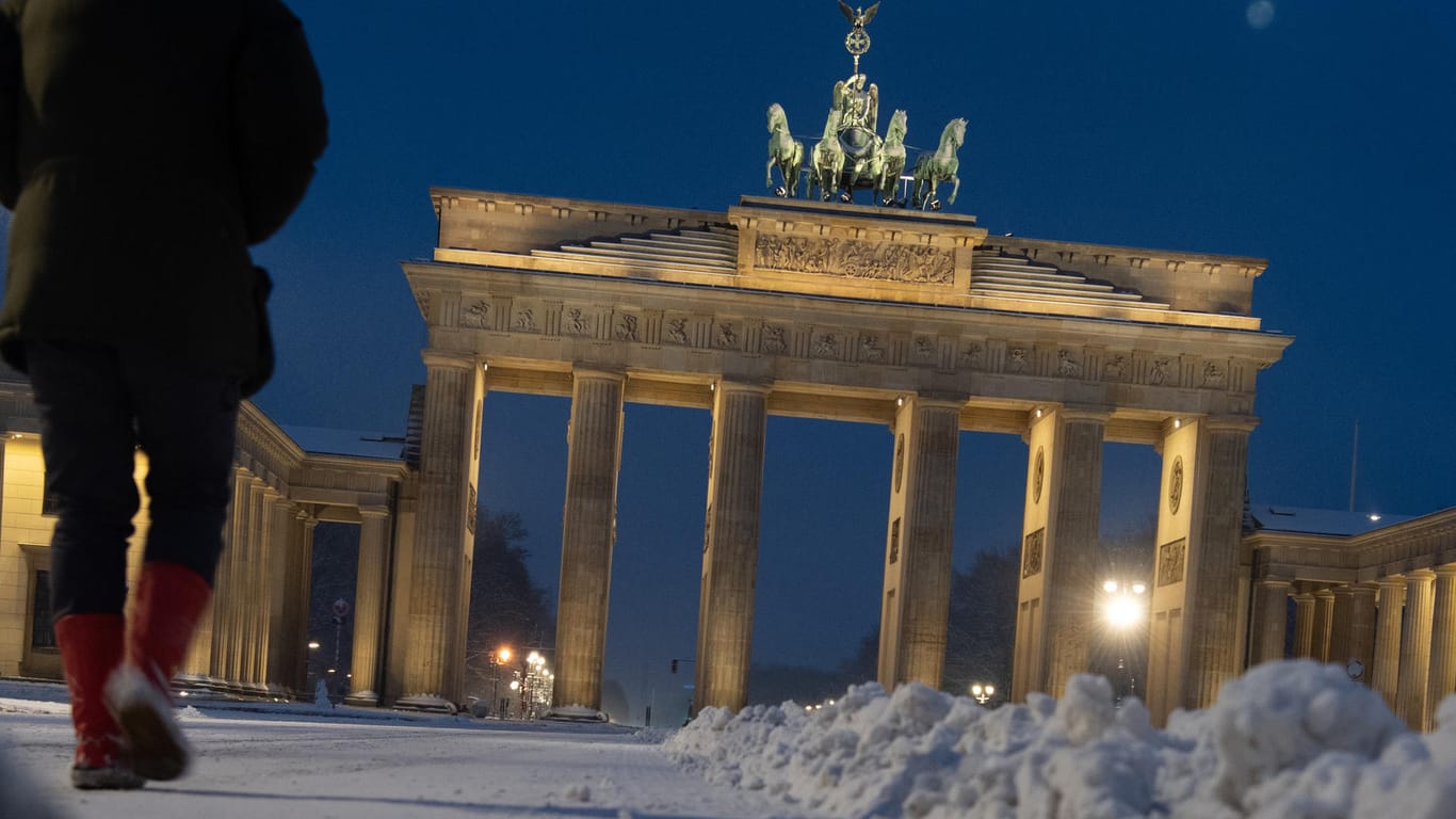 Ein Mann geht am frühen Samstagmorgen über den mit Schnee bedeckten Pariser Platz am Brandenburger Tor: In der Hauptstadt hat es über Nacht geschneit.