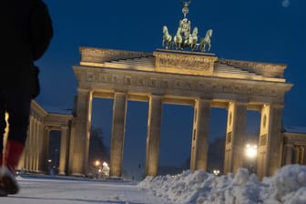 Ein Mann geht am frühen Samstagmorgen über den mit Schnee bedeckten Pariser Platz am Brandenburger Tor: In der Hauptstadt hat es über Nacht geschneit.