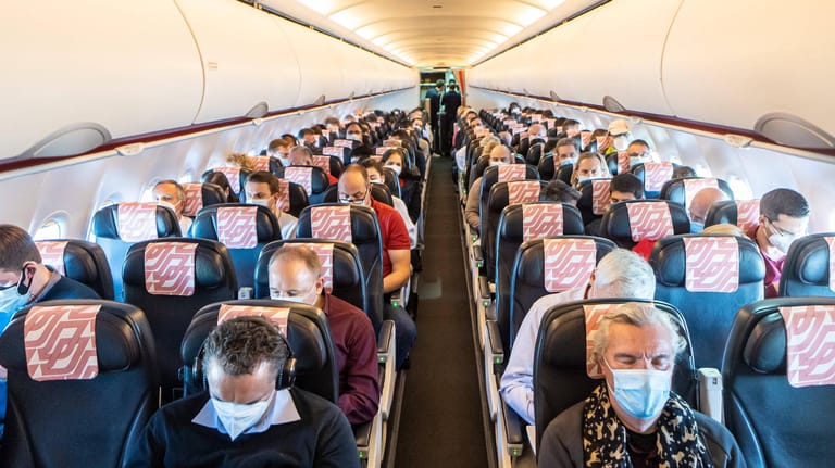 Passagiere in einem Flugzeug: Fluggesellschaften halten die aktuellen Corona-Vorschriften nicht immer ein.