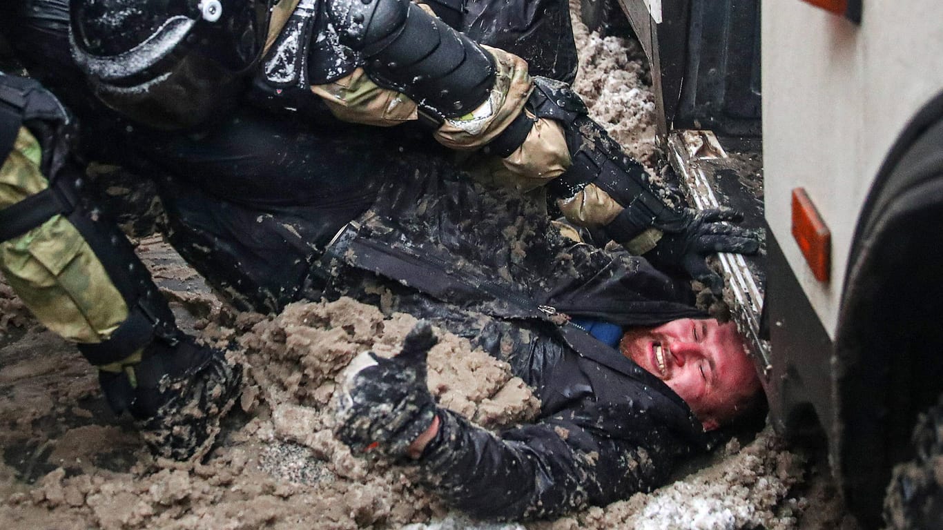 Polizeigewalt in Moskau: Ein Demonstrant liegt im dreckigen Schnee, während Sondereinsatzkräfte ihn angehen.