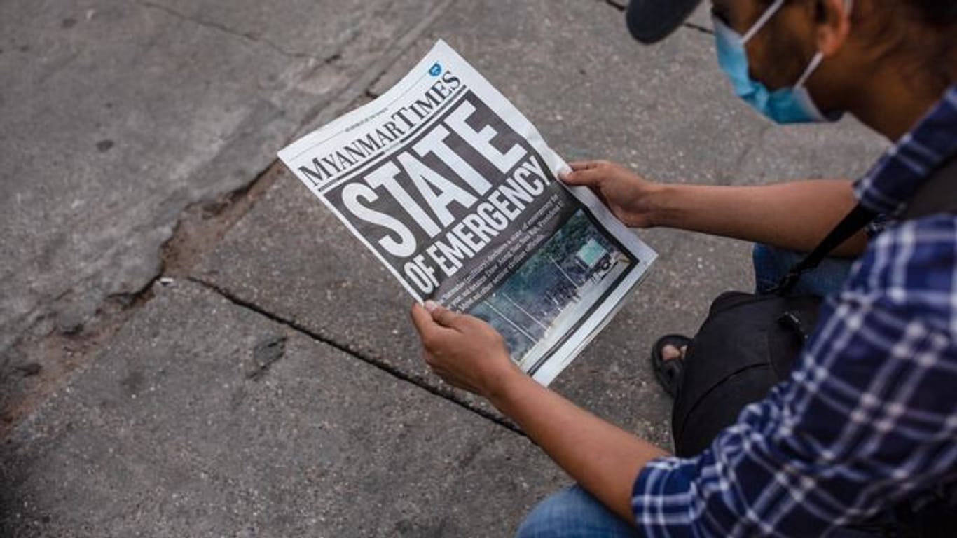 Ein Mann liest in Rangun die Zeitung "Myanmar Times" mit der Schlagzeile "Ausnahmezustand".