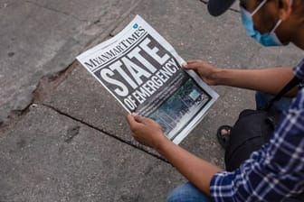 Ein Mann liest in Rangun die Zeitung "Myanmar Times" mit der Schlagzeile "Ausnahmezustand".