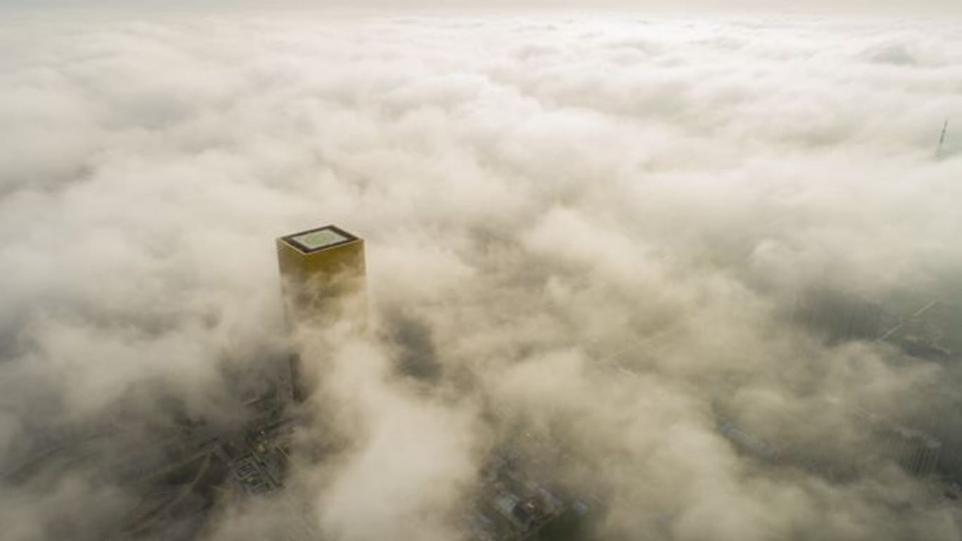 Ein Gebäude mit einem Hubschrauberlandeplatz ragt aus dem Smog über Pekings Innenstadt hervor.