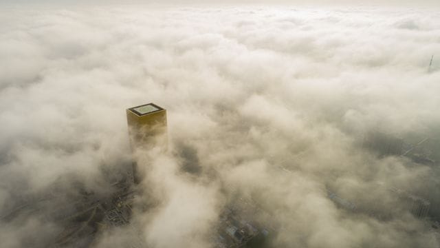 Ein Gebäude mit einem Hubschrauberlandeplatz ragt aus dem Smog über Pekings Innenstadt hervor. Ein Gebäude mit einem Hubschrauberlandeplatz ragt aus dem Smog über Pekings Innenstadt hervor.