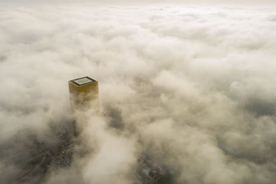Ein Gebäude mit einem Hubschrauberlandeplatz ragt aus dem Smog über Pekings Innenstadt hervor.