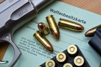 Eine Kaliber 9 mm Pistole, Patronen und ein Magazin liegen auf einer Waffenbesitzkarte.