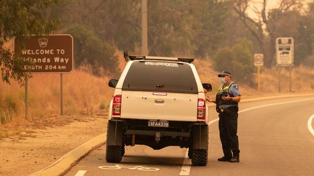 Die Polizei spricht bei einer Straßensperre auf der Great Northern Autobahn mit Anwohnern, die versuchen, in ihre Häuser zurückzukehren.