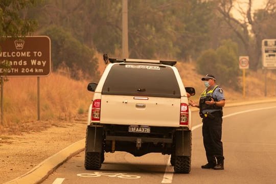 Die Polizei spricht bei einer Straßensperre auf der Great Northern Autobahn mit Anwohnern, die versuchen, in ihre Häuser zurückzukehren.