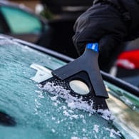 Eiskratzen bei einer gefrorenen Autoscheibe: Mit diesen Must-haves kommen Autofahrer gut durch den Winter.