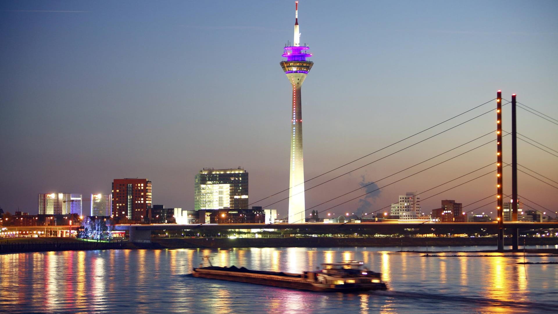 Ein Frachtschiff fährt nachts auf dem Rhein in Düsseldorf (Symbolbild): Ein Frachter ist auf Höhe des Heerdter Krankenhauses auf Grund gelaufen.