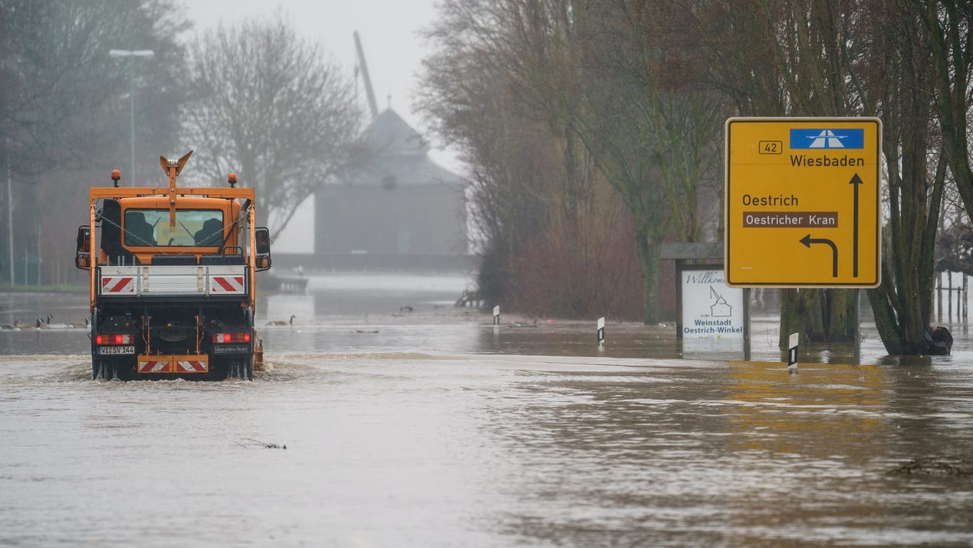 Hessen, Oestrich-Winkel: Ein städtisches Fahrzeug befährt die überschwemmte und gesperrte B42.