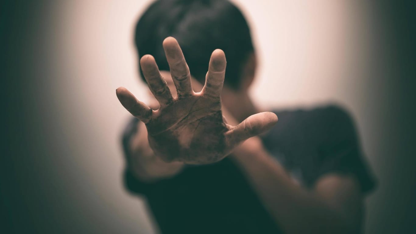 Ein Jugendlicher hält sich schützend die Hände vors Gesicht (Symbolbild): Eine Mutter aus Düsseldorf schaute tatenlos zu, wie ihr Sohn misshandelt wurde – nun wurde die Frau verurteilt.