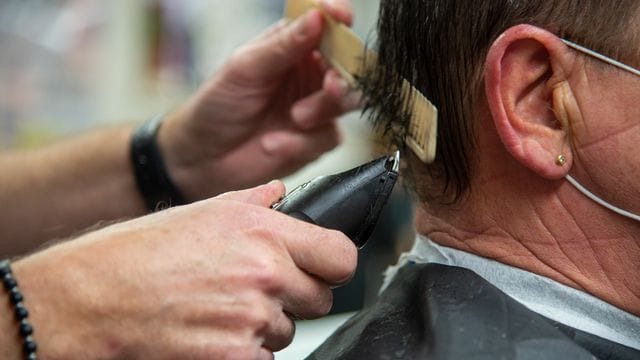 Ein Friseur schneidet einem Kunden die Haare