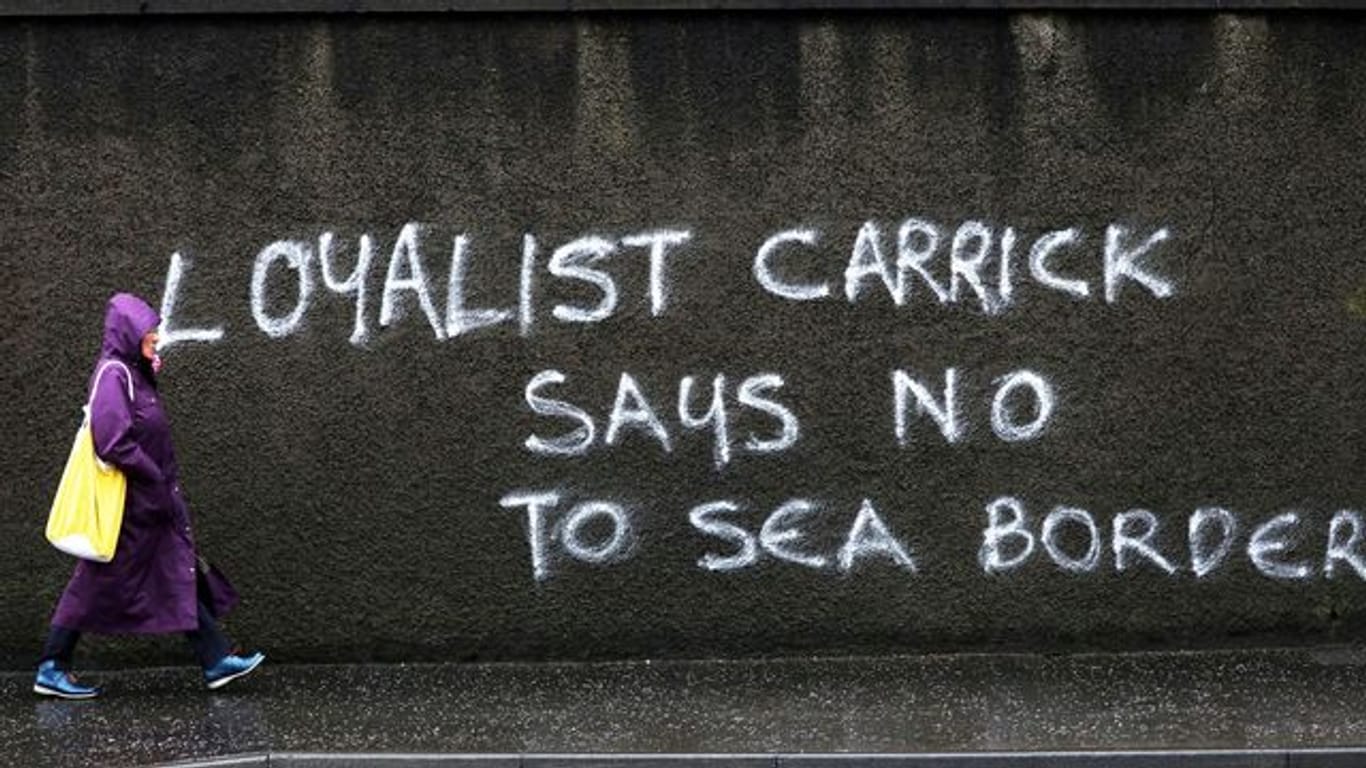 Eine Passantin geht in Belfast an einem Graffiti mit dem Schriftzug "Loyalist Carrick says no to Sea Border" (Loyalist Carrick sagt Nein zur Seegrenze) vorbei.