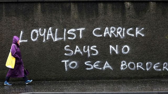 Eine Passantin geht in Belfast an einem Graffiti mit dem Schriftzug "Loyalist Carrick says no to Sea Border" (Loyalist Carrick sagt Nein zur Seegrenze) vorbei. Eine Passantin geht in Belfast an einem Graffiti mit dem Schriftzug "Loyalist Carrick says no to Sea Border" (Loyalist Carrick sagt Nein zur Seegrenze) vorbei.