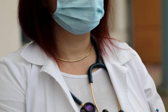 Eine Ärztin mit medizinischem Mundschutz und Stethoskop (Symbolbild): In Köln wurde die Praxis einer Hausärztin durchsucht, die gegen Coronaregeln verstoßen haben soll.