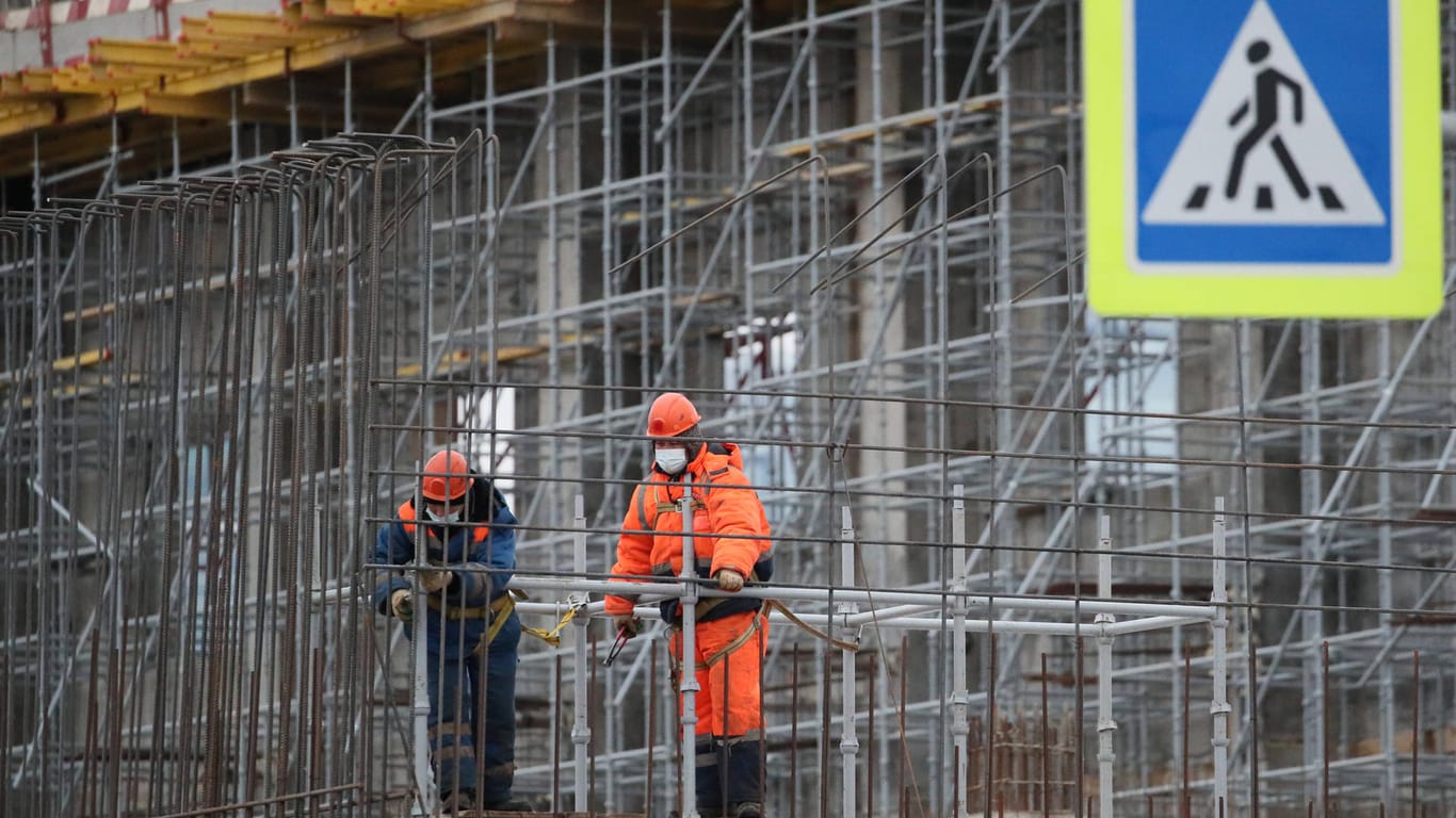 Arbeiter stehen auf einem Gerüst (Symbolbild): In Köln ist ein Baugerüst umgestürzt und hat einen Mann lebensgefährlich verletzt.