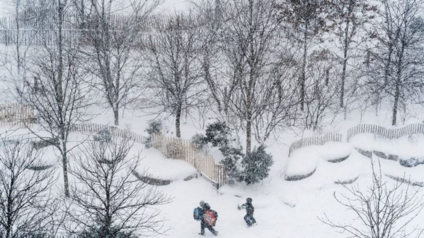 Menschen gehen bei Schneefall Schlittenfahren (Symbolbild): Obwohl Schneestürme für den Norden angesagt waren, müssen Bürger nicht mit viel Schnee rechnen.