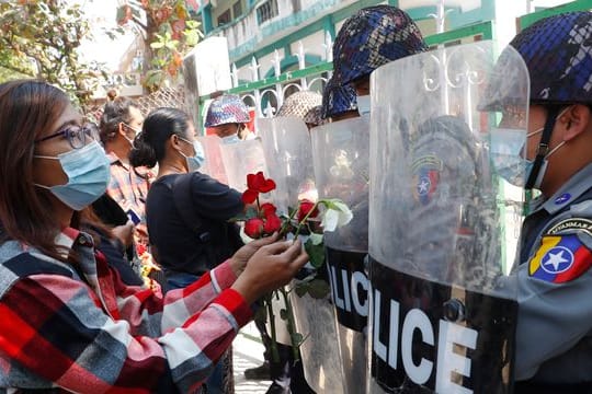 Demonstranten in Mandaley überreichen der Polizei Rosen, während vier festgenommene Aktivisten vor Gericht erscheinen.