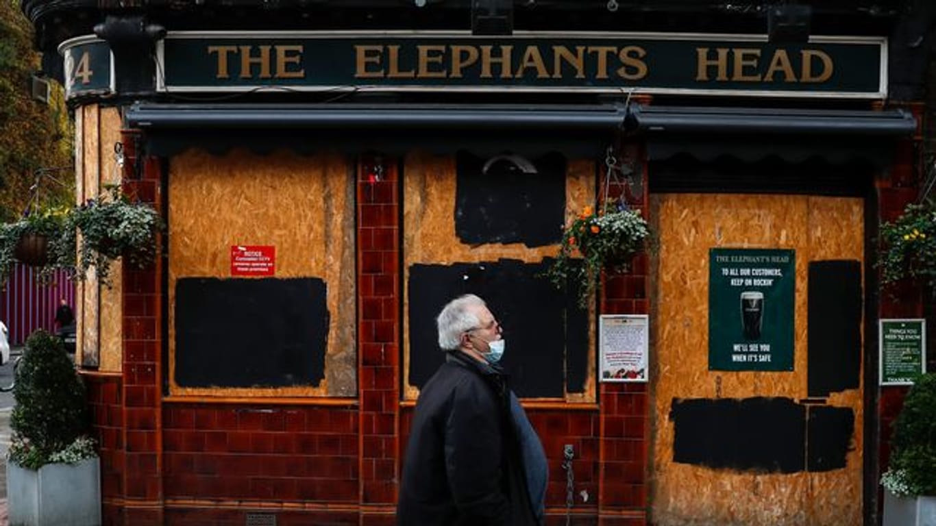 Ein Mann geht an einem geschlossenen Pub in London vorbei.