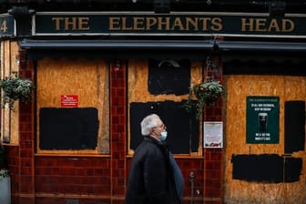 Ein Mann geht an einem geschlossenen Pub in London vorbei.