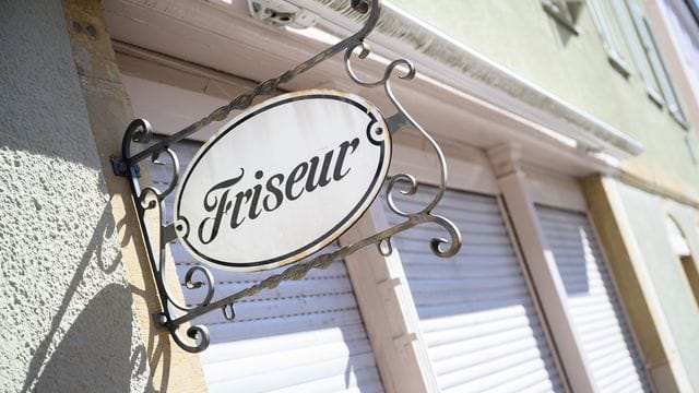 Ein Schild mit der Aufschrift "Friseur" hängt an einem geschlossenen Friseursalon. Ein Schild mit der Aufschrift "Friseur" hängt an einem geschlossenen Friseursalon.