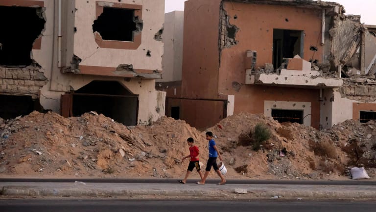 Jungen laufen an zerstörten Häusern vorbei: Seit fast zehn Jahren tobt in Libyen ein Bürgerkrieg.