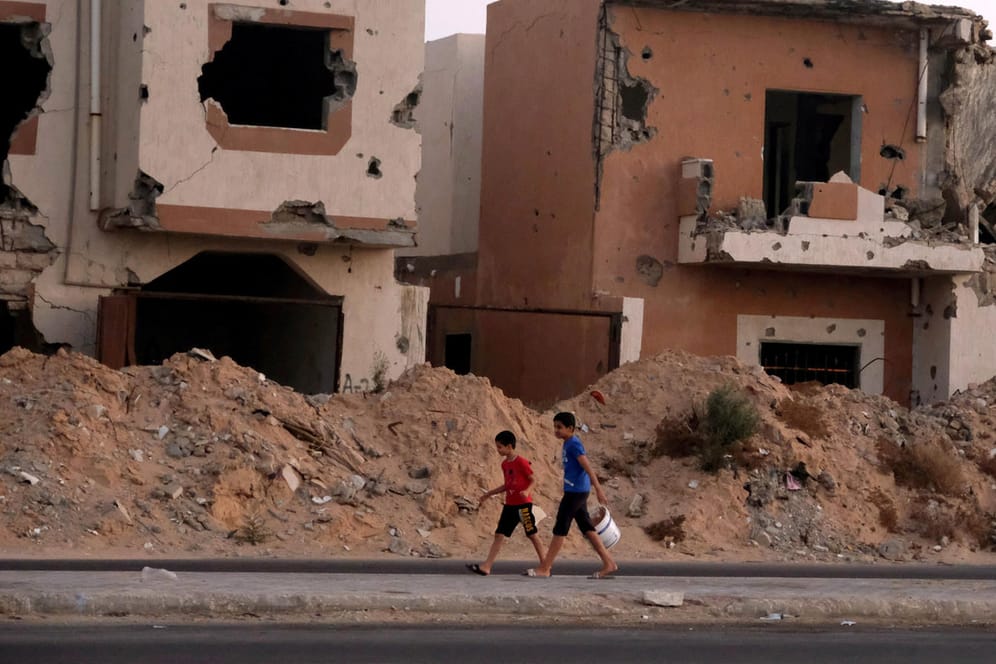 Jungen laufen an zerstörten Häusern vorbei: Seit fast zehn Jahren tobt in Libyen ein Bürgerkrieg.