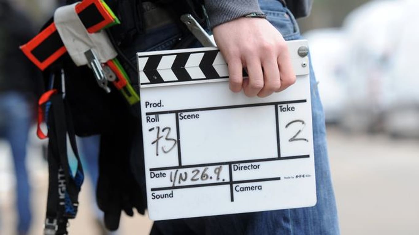 Ein Mitarbeiter eines Filmteams hält eine Filmklappe.