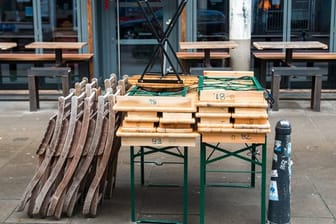 Zusammengestellte Tische und aufgestapelte Stühle stehen vor einem geschlossenen Café in Hamburg.