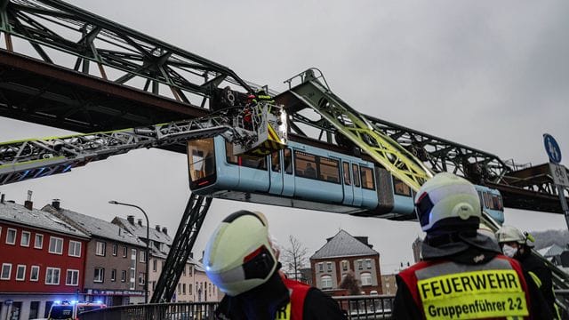 Einsatzkräfte der Feuerwehr befreien mit einer Drehleiter Fahrgäste aus einem Wagen der Schwebebahn, die wegen des eisigen Wetters stehen geblieben ist.