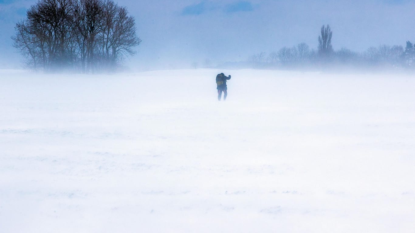 Ein Mann läuft über einen verschneiten Acker auf Rügen.