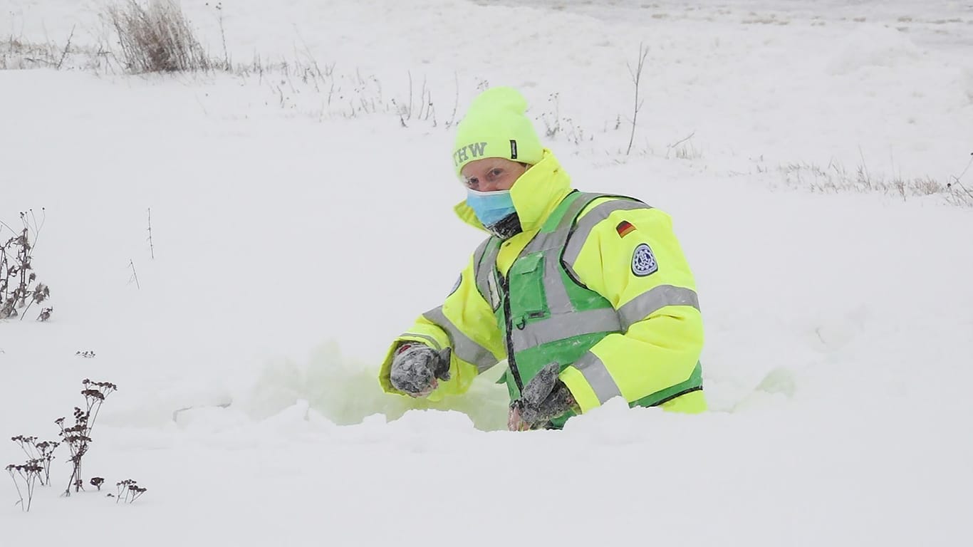 Ein Mitarbeiter des Technischen Hilfswerks steckt in einer hohen Schneewehe an der gesperrten Zufahrt zur Autobahn A7 in Bockenem, Niedersachsen.