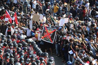 Demonstranten zeigen in Naypyitaw den Dreifingergruß und ein durchgestrichenes Foto des Generals Min Aung Hlaing.