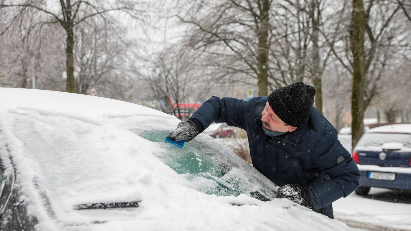 Wintereinbruch in Wuppertal: In Vohwinkel versucht ein Mann die zentimeterdicke Eisschicht von der Frontscheibe seines Wagens zu kratzen. Der Schnee hat in der Stadt für Behinderungen im Verkehr gesorgt.