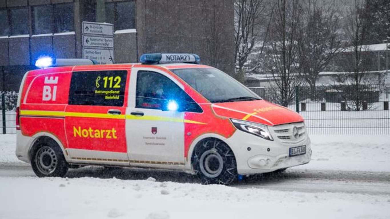 Ein Notarztwagen vom Rettungsdienst fährt mit Blaulicht auf einer zugeschneiten Straße in Bielefeld.