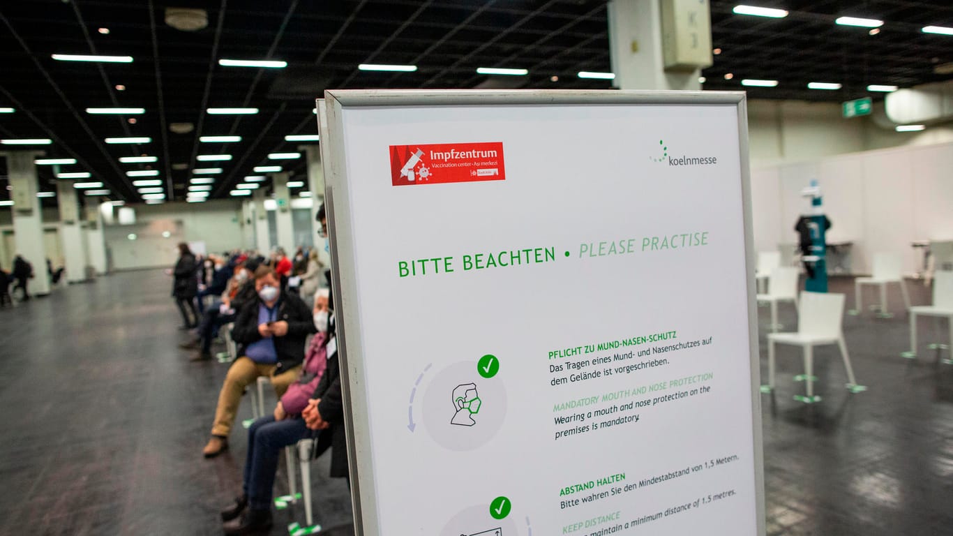 Ein Schild weist auf Maskenpflicht und Abstandsregeln hin: Am Montag wurde das Impfzentrum in den Kölner Messehallen eröffnet.