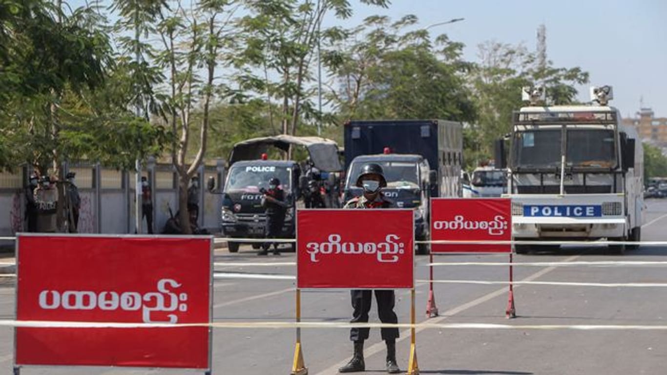 Polizisten stehen Wache auf einer abgesperrten Straße in Mandalay, auf der es am Vortag zu Zusammenstößen mit Demonstranten gekommen war.