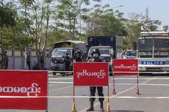 Polizisten stehen Wache auf einer abgesperrten Straße in Mandalay, auf der es am Vortag zu Zusammenstößen mit Demonstranten gekommen war.