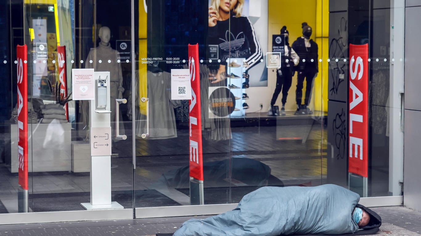 Ein Obdachloser liegt mit Mundschutz und in einem Schlafsack in der Kölner Innenstadt: Die Corona-Krise und die Kältewelle treffen Menschen auf der Straße besonders.