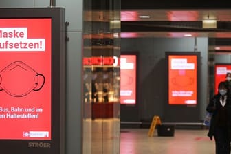 Der Schriftzug "Maske aufsetzten" steht im Kölner Hauptbahnhof auf einem Display.