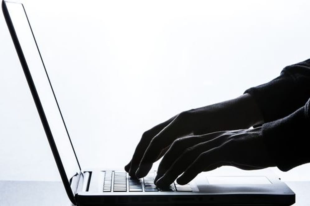 Ein Mann tippt auf einer Tastatur eines Laptops.