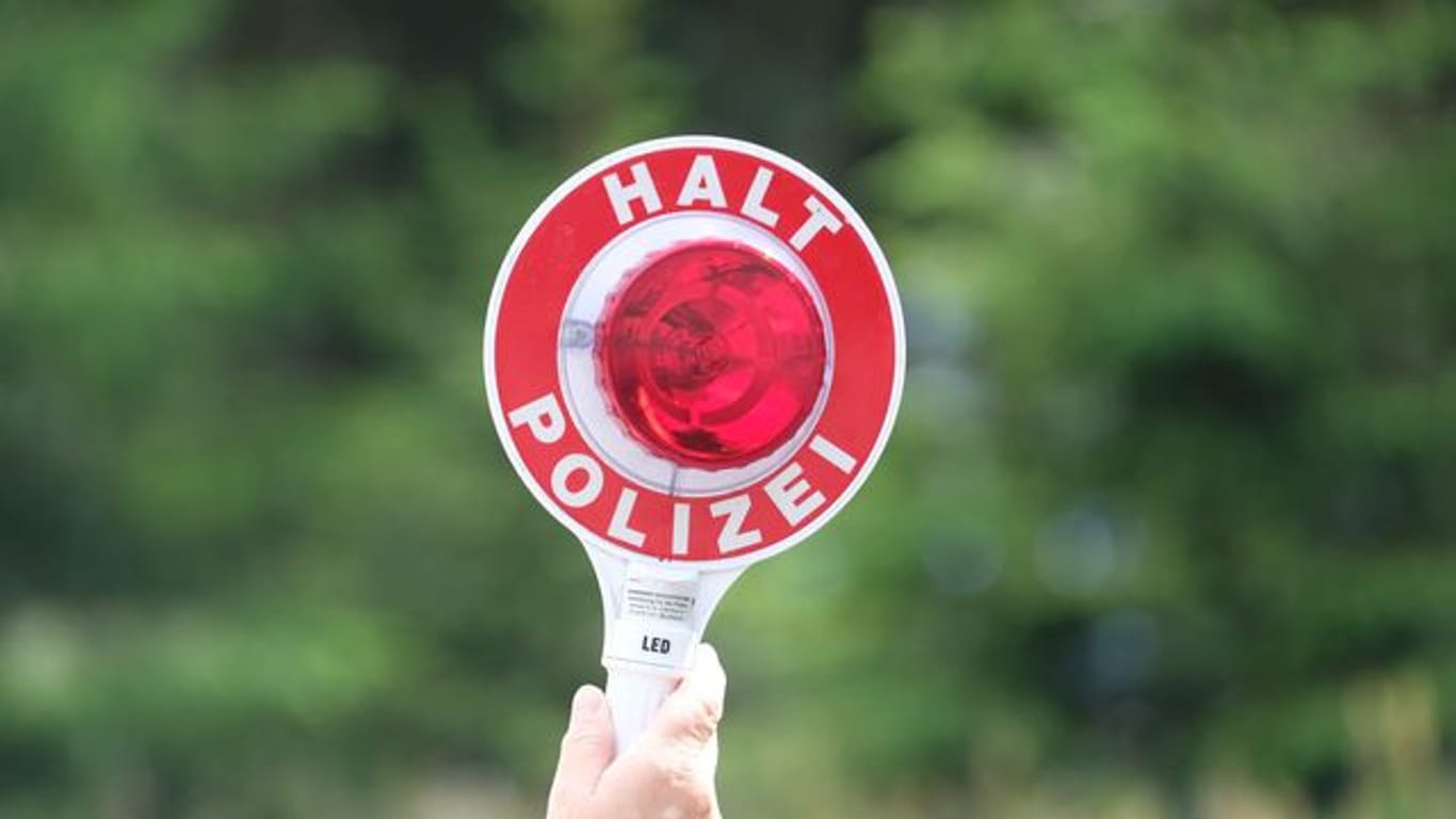 Eine Polizistin hält eine rote Winkerkelle in die Höhe (Symbolbild): In Stuttgart hat die Polizei womöglich ein illegales Autorennen gestoppt.