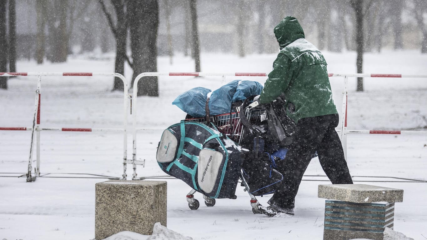 Ein Obdachloser mit einem Einkaufswagen im Schnee (Symbolbild): Stuttgart weist auf die Notunterkünfte für Wohnungslose hin.