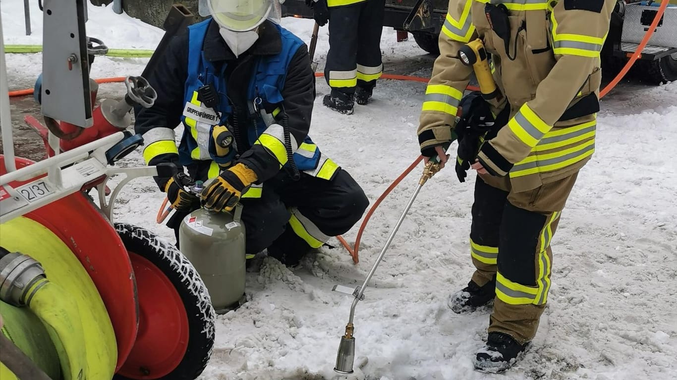 Zwei Feuerwehrmänner legen mit einem Gasbrenner den Hydrantendeckel unter dem Schnee frei: Der Schnee und die Kälte erschweren der Feuerwehr die Arbeit.