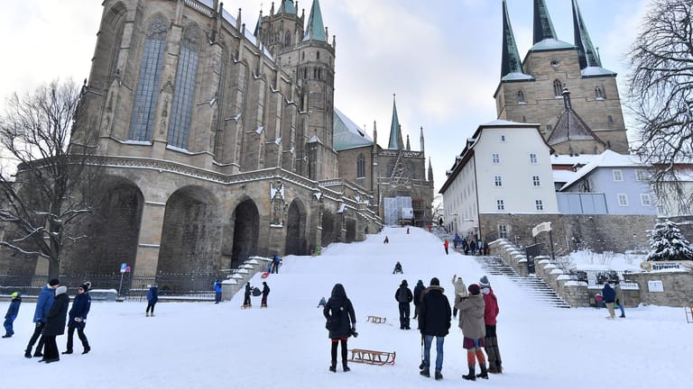 Menschen mit Schlitten stehen auf dem Domplatz: Das Erfurter Dombauamt will dem winterlichen Treiben auf den Domstufen ein Ende setzen.