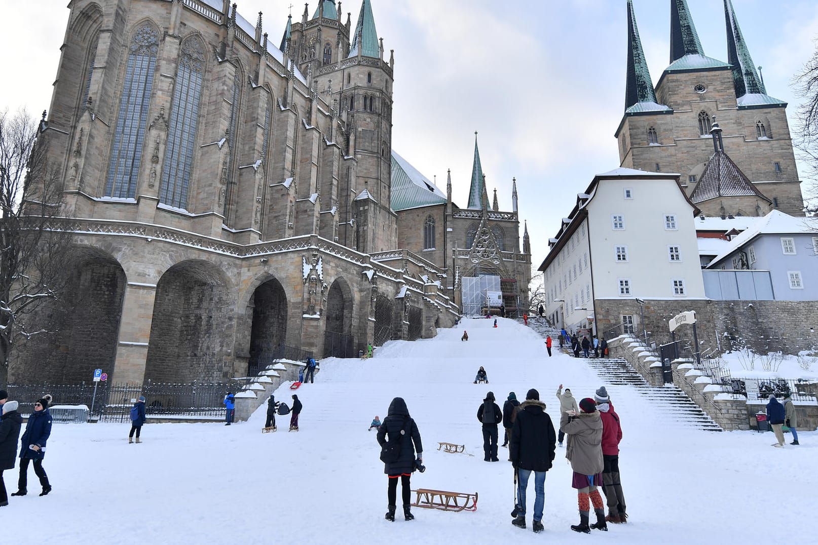 Menschen mit Schlitten stehen auf dem Domplatz: Das Erfurter Dombauamt will dem winterlichen Treiben auf den Domstufen ein Ende setzen.