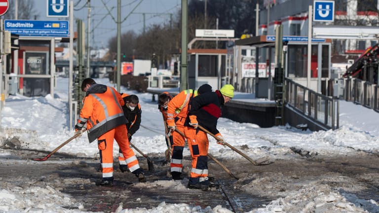 Mitarbeiter des Nahverkehrsbetreibers Dortmunder Stadtwerke DSW21 versuchen mit Schaufeln Straßenbahnschienen an einer Straßenkreuzung vom Schnee zu befreien: In der Stadt haben Schneemassen für Beeinträchtigungen gesorgt.