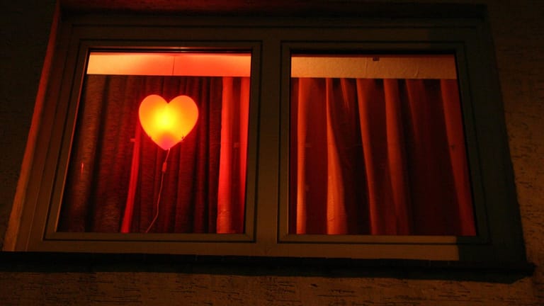 Ein rot leuchtendes Herz hängt in einem Fenster (Symbolbild): Die Essener Polizei hat drei Personen wegen des Verdachts auf illegale Prostitution festgenommen.